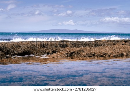 Ocean waves break beyond shallow tide pools at Wahikuli Wayside Park on Maui, Hawaii.
