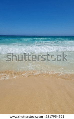 Ocean Waves Breaking On Sandy Shoreline Under Clear Blue Sky