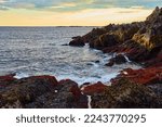Ocean waves crashing on Maine coast in low tide with golden light