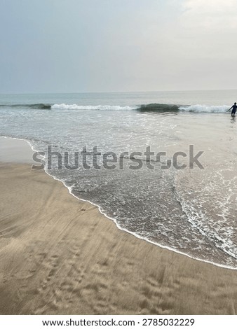 Ocean waves reaching sandy beach shoreline under cloudy sky, peaceful tropical seascape and relaxing coastal travel destination