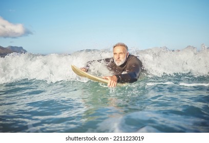 Ocean waves, senior man surfing on beach and healthy fitness lifestyle in Australia summer holiday. Elderly surfer swimming with surfboard, sea water exercise and relax in retirement travel vacation - Powered by Shutterstock