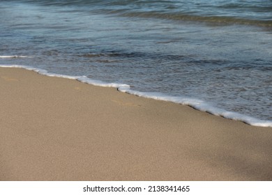 Ocean's Foam And Wet Sand. Close Up On A Wave And Sandy Beach. 