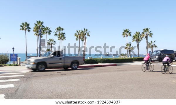 Oceanside, California USA - 8 Feb 2020: Person\
riding bicycle on road, tropical beach palm trees. Biker cycling\
bike, healthy lifestyle sport hobby. People on waterfront Pacific\
street, coastal\
suburb