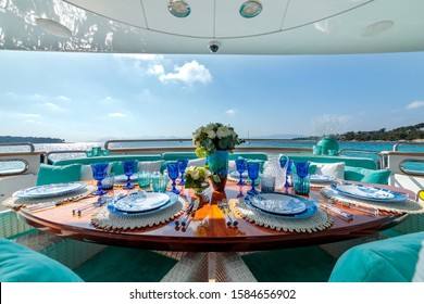 An ocean-themed table setting with blue plates, wine glasses and a flower bouquet on a luxury yacht