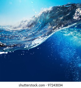 ocean-view seascape landscape with blue sky and sunlight big curly ocean wave splitted by waterline to underwater part with air bubbles