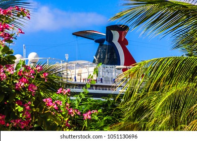 Ocho Rios, Jamaica - February 20, 2018: Carnival Vista Cruise Ship Funnel Viewed Through A Opening In Green Plants With Red Flowers And Palm Trees. Cruise Ship Chimney.