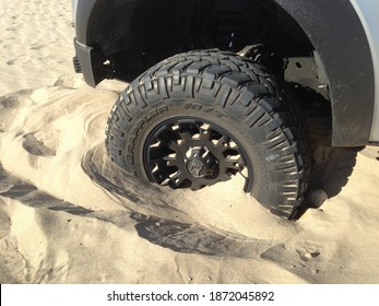 Ocotillo Wells, CA USA - circa November 2016: Close up of a all-terrain truck tire stuck axle deep in desert sand 