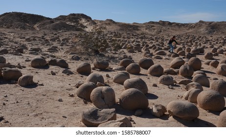 Ocotillo Wells, CA / USA - November 26, 2019: A young person enjoys jumping around on the globular sandstone concretions at Pumpkin Patch.                               