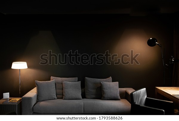 OCT 26, 2012 Barcelona, Spain - Modern dark tone\
living room with gray fabric sofa couch and spot lighting on black\
wall from well design lamps
