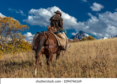 OCT 4, 2017, RIDGWAY COLORADO - Older Cowboy, Howard Linscott , leads packhorse across historic Last Dollar Ranch on Hastings Mesa, SW Colorado, San Juan Mountains