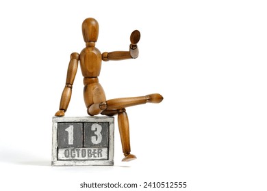 October 13, wooden calendar with mannequin sitting on it on white background. Calendar date