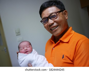 October 18, 2018. Chon Buri, Thailand. Grandpa Visit The Newborn Grandchild And Are Holding And Looking At The Baby With A Smile And Love At The Hospital.