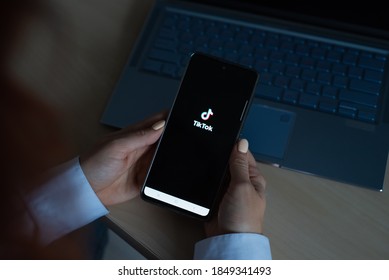 October 18, 2020 Russia Novosibirsk: A Woman Holds A Phone With The Tik Tok Logo On The Screen. The Girl Is Watching A Mobile Application With Funny Videos