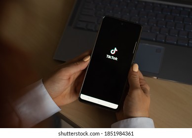 October 18, 2020 Russia Novosibirsk: A Woman Holds A Phone With The Tik Tok Logo On The Screen. The Girl Is Watching A Mobile Application With Funny Videos