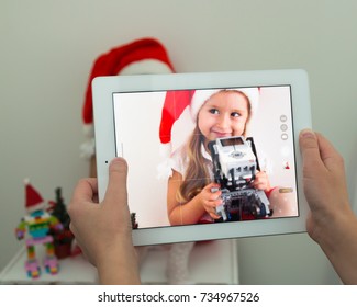 October, 2017. Minsk, Belarus. The boy makes a photo on IPad Apple of a cute little girl in a Santa Claus hat. She holds the Dog Lego robot. Concept New Year 2018 and Christmas.  STEM education.