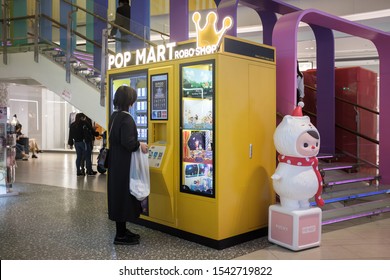 October 2019, Shanghai: A POP MART Robo Shop Plased In A Mall. A Young Chinese Woman Standing In Front Of A POP MART Robo Shop Vending Machine.