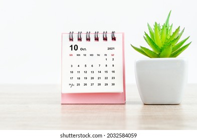 October 2021 Desk Calendar With Small Tree On Wooden Table.