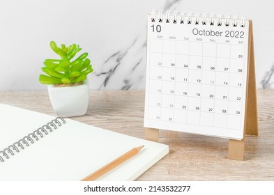 The October 2022 desk calendar with plant on wooden table. - Shutterstock ID 2143532277