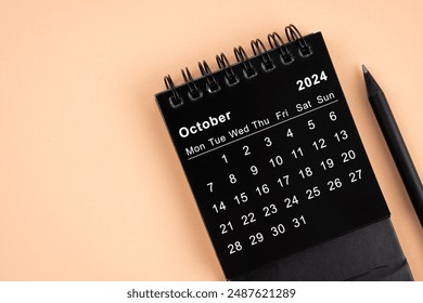 October 2024 Black spiral desktop calendar and wooden pencil on yellow background. - Powered by Shutterstock