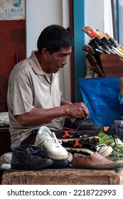 October 26, 2022 - Bandung, Indonesia : An Old Man Works Repairing Used Shoes To Survive In Front Of A Street Shop