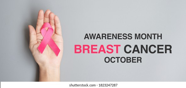 October Breast Cancer Awareness month, adult Woman  hand holding Pink Ribbon on grey background for supporting people living and illness. International Women, Mother and World cancer day concept