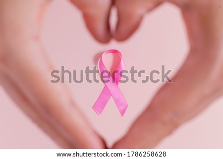October is Breast Cancer Awareness Month. Pink ribbon to support women with cancer. Heart shaped hands