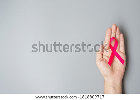 October Breast Cancer Awareness month, adult Woman  hand holding Pink Ribbon on grey background for supporting people living and illness. International Women, Mother and World cancer day concept