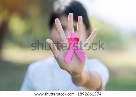 October Breast Cancer Awareness month, adult Woman hand holding Pink Ribbon for supporting people living and illness. International Women, Mother and World cancer day concept