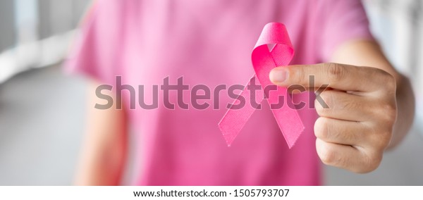 October Breast Cancer Awareness month, Woman in\
pink T- shirt with hand holding Pink Ribbon for supporting people\
living and illness. Healthcare, International Women day and World\
cancer day concept