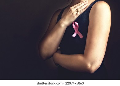 October is breast cancer awareness month,a woman holds a pink ribbon to support people living and sick.Health, international women's day and the concept of the world day of fight against cancer. - Shutterstock ID 2207475863