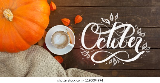 October hand lettering inscription. A cup of coffee with cappuccino and autumn leaves on old wooden background. Autumn decor, fall mood, autumn still life.