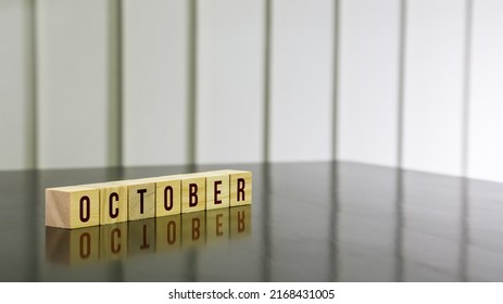 OCTOBER Word On Wooden Cube On Black Gloss Wooden Table. Selected Focus