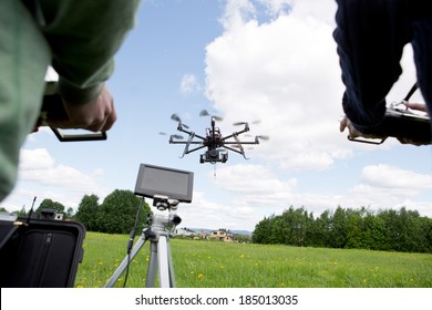 Octocopter being operated by a photographer and pilot in open green park