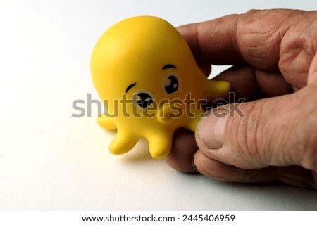 Octopus children bath toy.Childrens rubber toy octopus on white background side view.image of rubber toy white background .An octopus toy in the hand of an adult man.