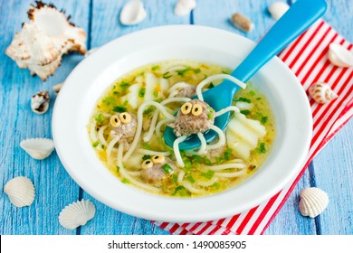 Octopus soup for kids lunch - potato soup with meatballs and spaghetti shaped funny octopuses in white bowl
