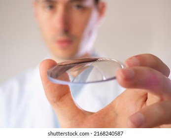 Oculist holds a lens in his hand. Eyewear lens.
