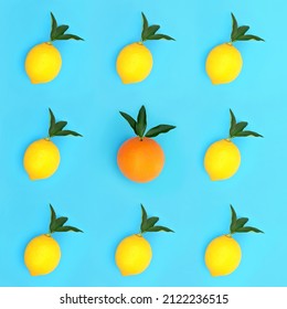 Odd One Out Concept With Lemon And Orange Fruit With Leaf Sprigs In A  Isometric Pattern On Blue Background. Minimal Contrast Abstract Design. High In Antioxidants, Bio Flavonoids And Vitamin C.