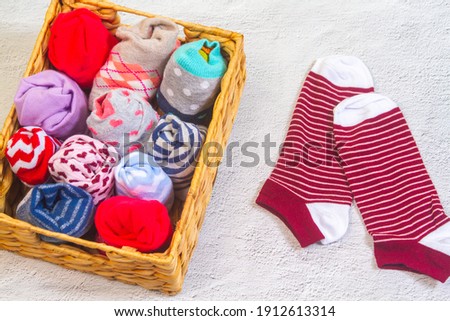 Odd sacks day, multi-colored socks twisted into one another in a woven straw basket.
