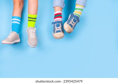 Odd Socks Day, Lonely Sock Day.  Anti-Bullying Week, Down syndrome awareness. Child legs wearing different pair of mismatched socks on high-colored background copy space