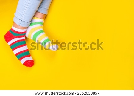 Odd Socks Day, Lonely Sock Day.  Anti-Bullying Week, Down syndrome awareness. Child legs wearing different pair of mismatched socks on high-colored background copy space