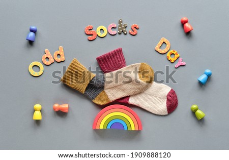 Odd Socks Day text. Pair of mismatched school socks on top of wood toy rainbow. Social initiative against bullying in school or workplace. Promotion design for anti-bullying campaign.
