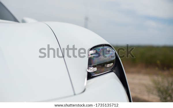 Odesa, Ukraine - May 11, 2020:
Porsche Taycan Turbo In a field near wind-driven electric
generators. Test drive Porsche Dealership Odesa Porsche
Center.