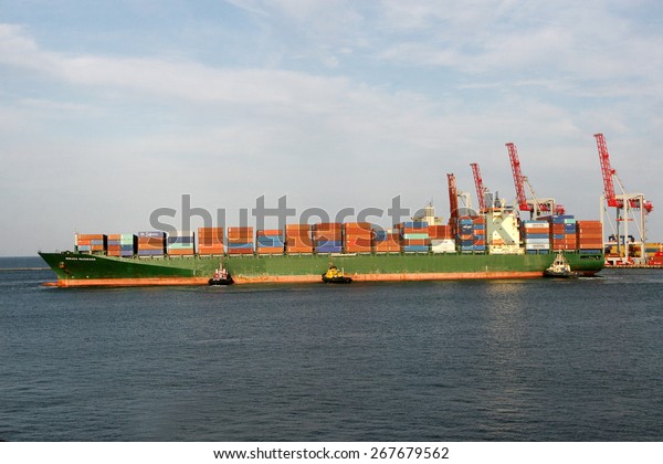 Odessa, Ukraine - 25 august 2008: Large marine ship
leaves the container terminal. Powerful marine pilot tug boat from
the output port of the bay to the open sea. Sea transportation of
cargo
