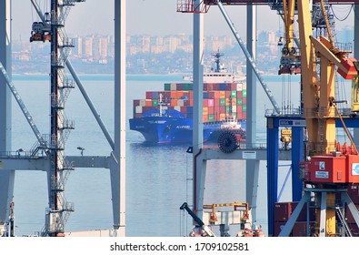 Odessa / Ukraine - April 09 2020: Seaport weekdays. Container ship ALLEGRI IMO 9127459 of ARKAS container operator inbound in port of Odessa. View through gantry cranes.