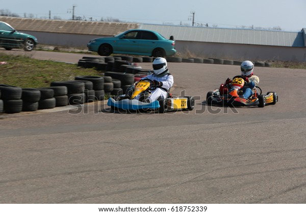 ODESSA, UKRAINE - April 2, 2017: karting\
championship. Kart drivers in helmet, racing suit participate in\
karting race. Carting show. Children, teenagers and adult kart\
racing drivers.