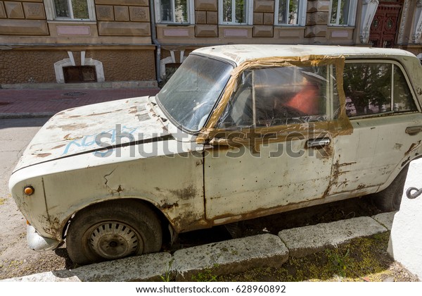 ODESSA, UKRAINE - April 25, 2017: An old abandoned\
car on city street. Rusty, worn-out old unnecessary design machine\
of  20th century rusts at  curb of  city street in poor, depressed\
quarter city
