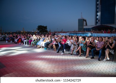 Odessa, Ukraine August 4, 2018: Rear View Of Crowd With Arms Outstretched At Concert. Silhouettes Of Concert Crowd In Front Of Bright Stage Lights. Crowd At Music Concert, Audience Raising Hands Up