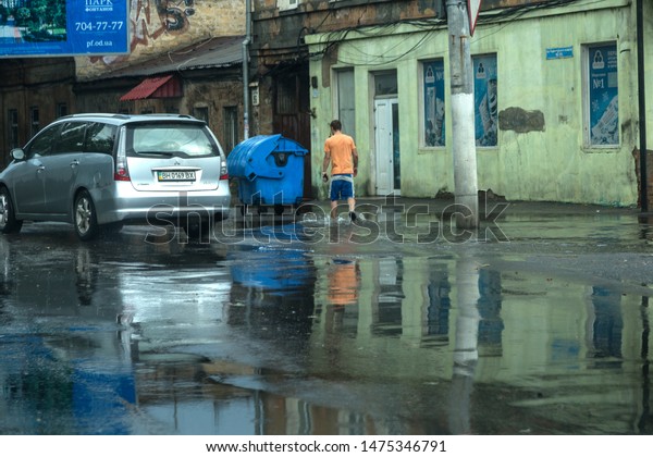Odessa, Ukraine -August 9,2019: driving car on\
flooded road during flood caused by torrential rains. Cars float on\
water, flooding streets. Splash on the car. Flooded city road with\
a large puddle