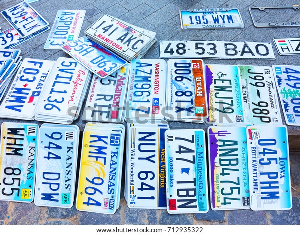Odessa, Ukraine - circa 2017: car numbers from\
around world. Discontinued license plate of cars from cars of\
Europe and United States on paving tiles. Vintage background\
antique license plates