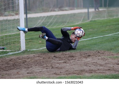 ODESSA, UKRAINE - CIRCA 2019: A Goalkeeper Of A Local Football Team Makes A Save While Playing In A Regional Derby Championship On A Bad Football Field. Soccer Goal, Goal Net